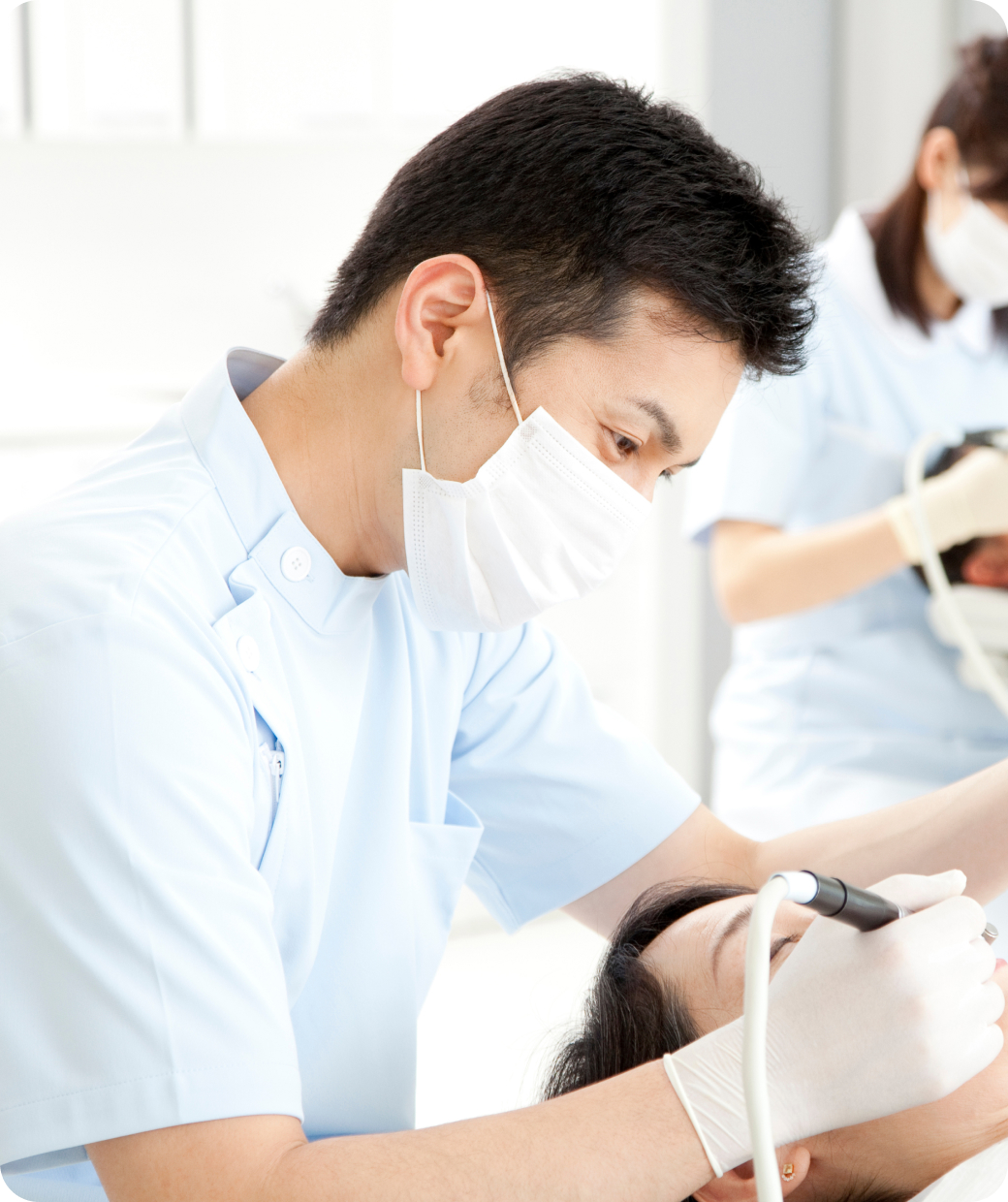 歯の治療を受けている患者と、それをサポートする医師とスタッフ